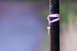 Key on purple string hanging on wood post